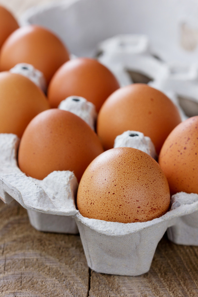 Chicken eggs in a carton box on a wooden rustic table