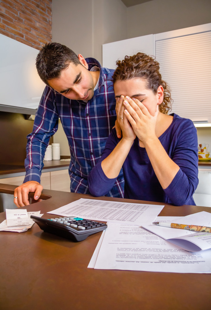 Young guy friend gives solace to desperate unemployed woman crying by her debts. Financial problems concept.