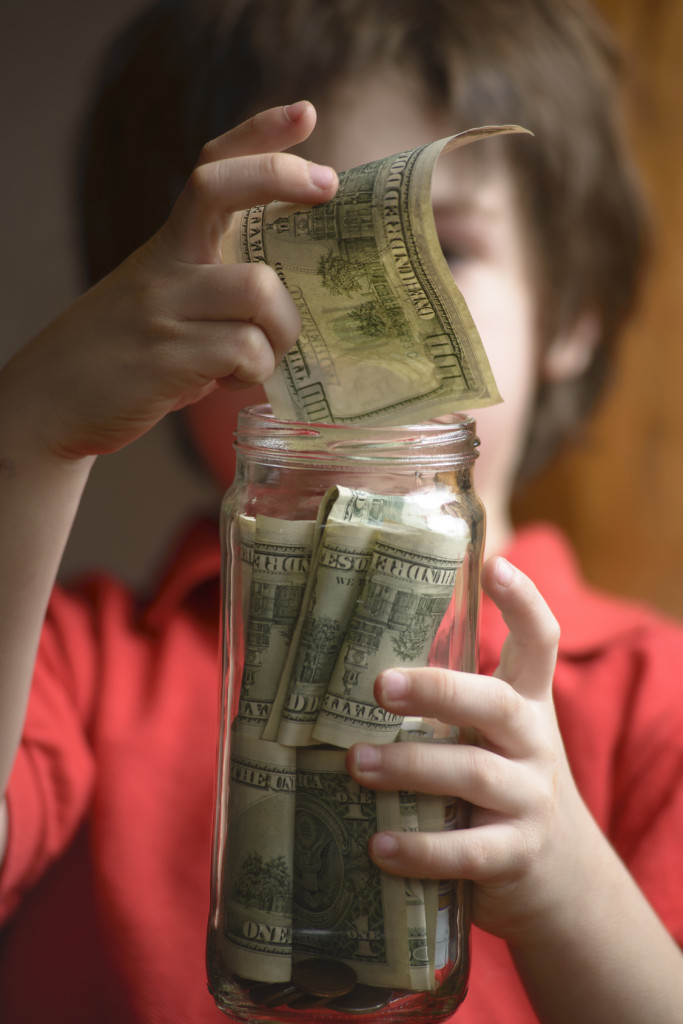 Child entering their savings in a jar