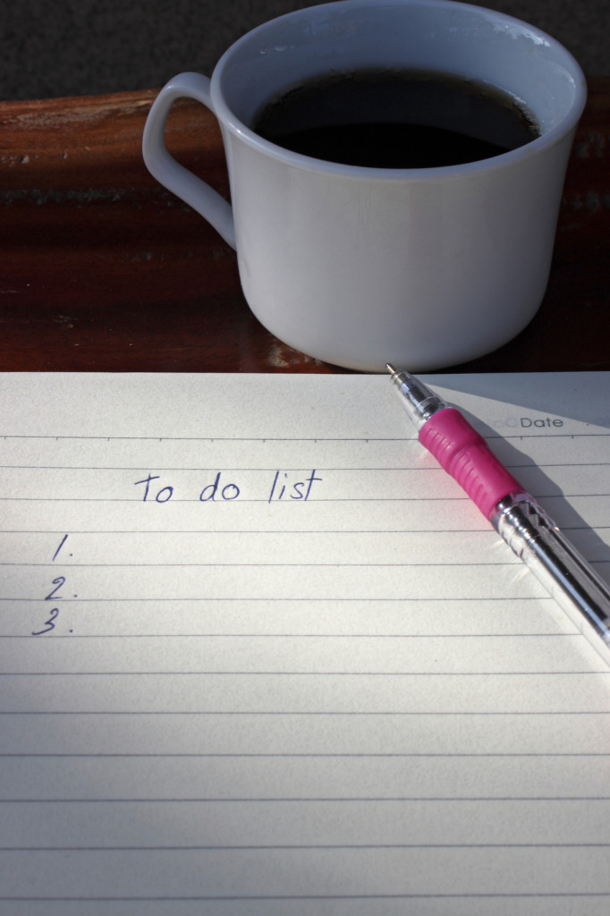 To do list with a pen and cup of fresh coffee on wood background in morning