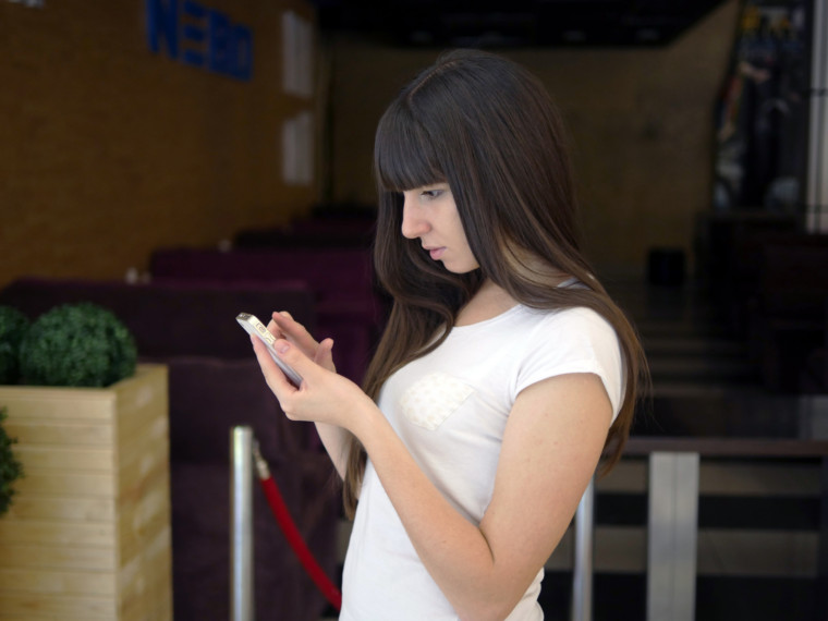 Young woman playing Pokemon GO indoor at cafe, using smart phone. Girl play the popular smartphone game - catching pokemon