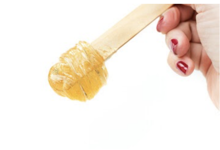 A master stir the sugar paste before removing unwanted hair - Sugaring